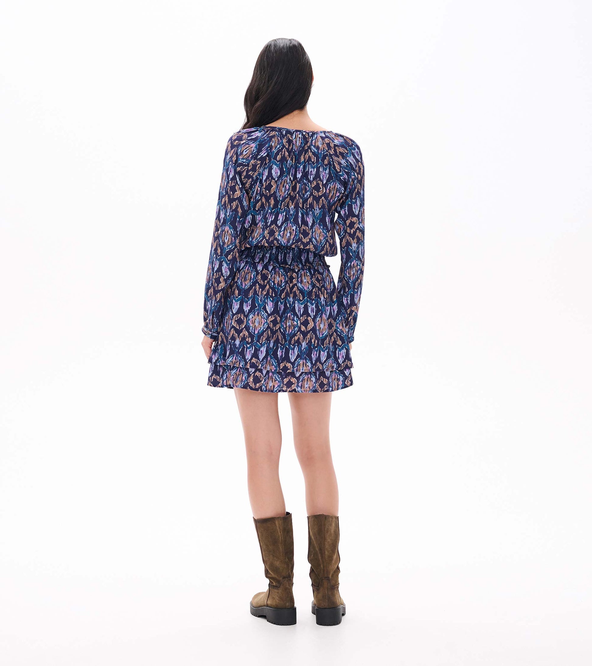 Back view of navy ikat print mini dress with long sleeves, smocked waist, and tiered ruffle skirt