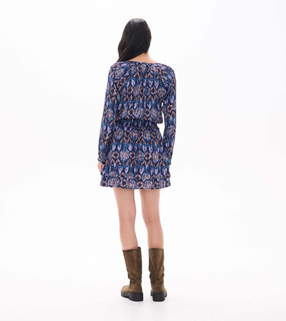 Back view of navy ikat print mini dress with long sleeves, smocked waist, and tiered ruffle skirt