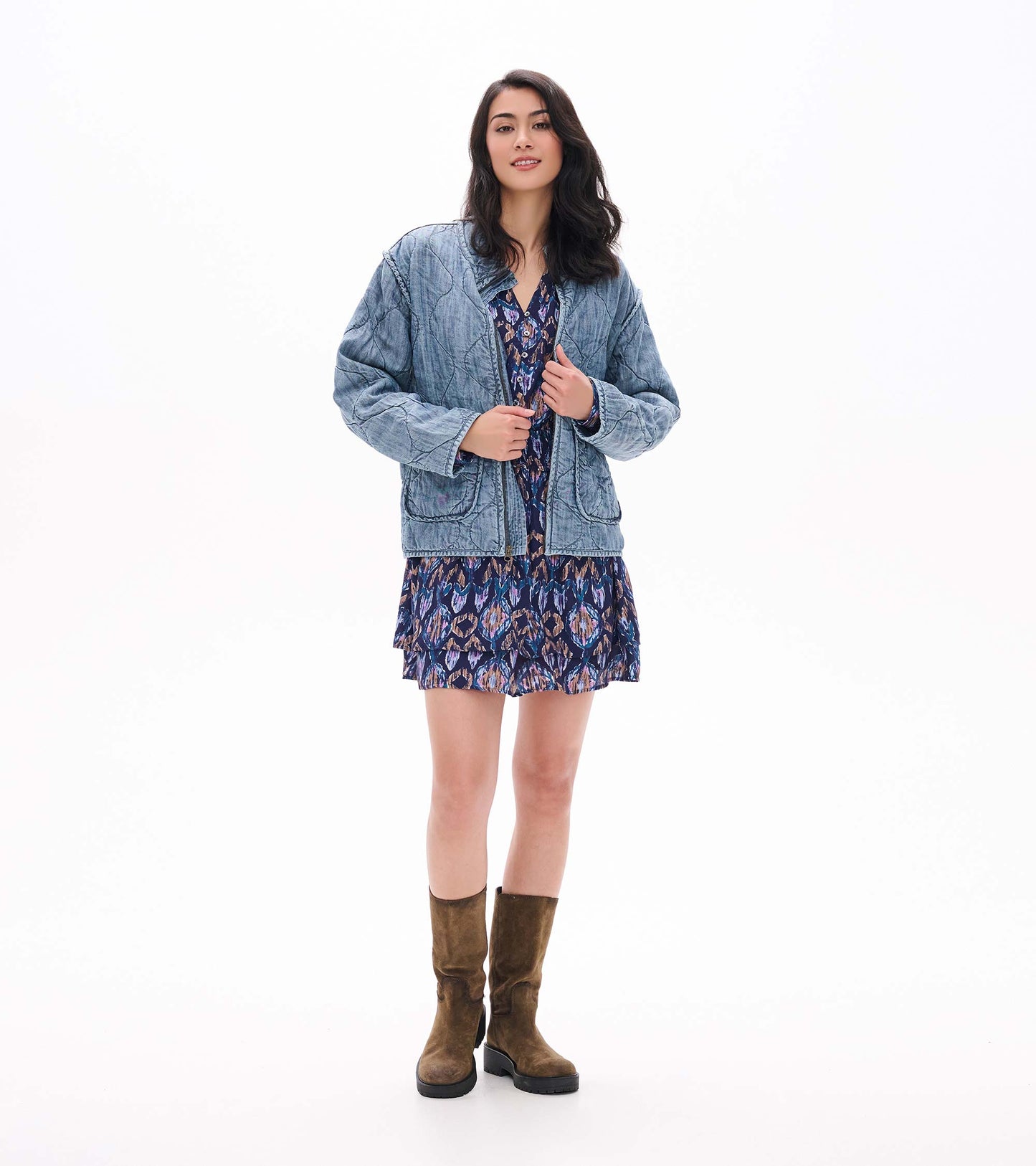 Front view of navy textured ikat mini dress with button placket, layered skirt, and smocked waist under a blue jacket