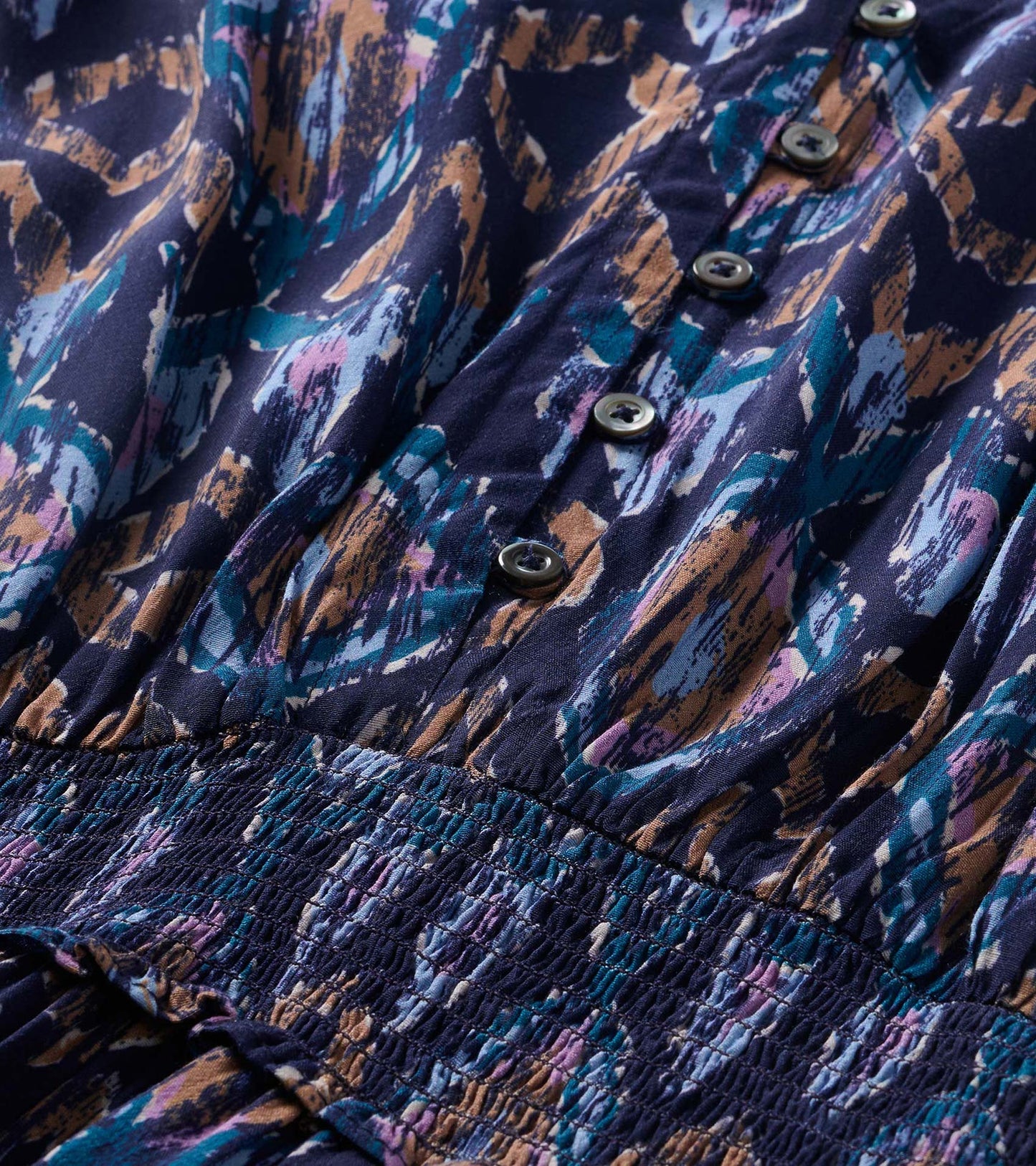 Close-up of navy textured ikat print dress with front buttons and smocked waist detail