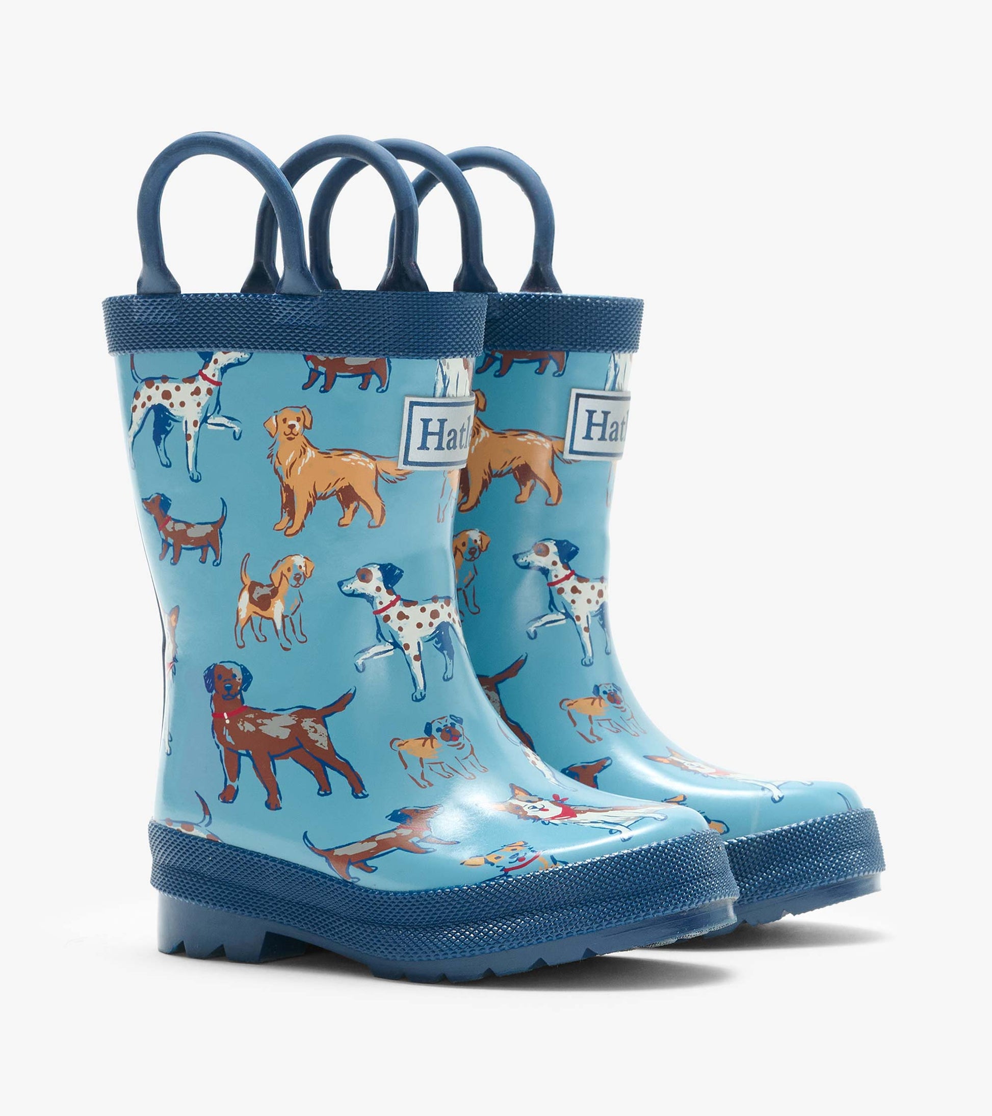 Pair of blue kids rain boots with navy handles and a multicolor dog print, shown from the front