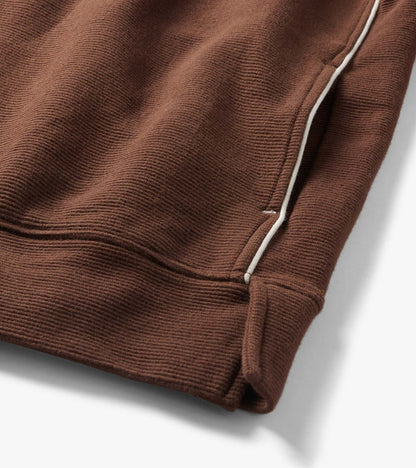 Close-up of the Fondue Fudge 1/4 zip top hem with ribbed texture, side seam, and white piping detail