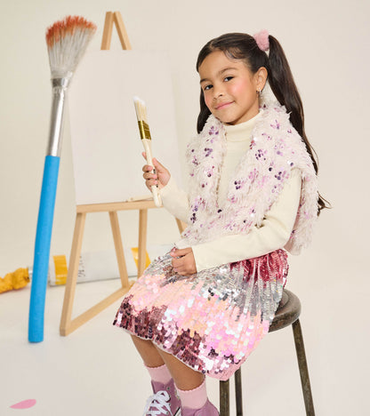 Girl seated wearing a pink and silver gradient sequin skirt with a silver glitter waistband