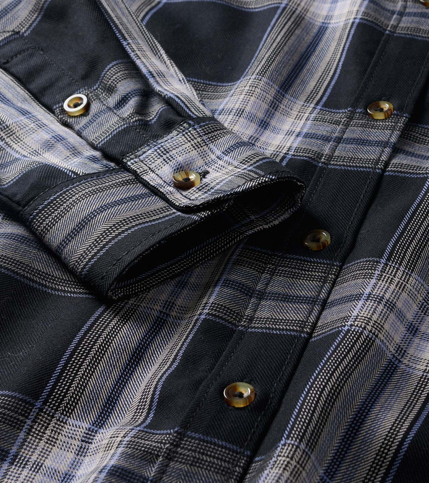 Close-up of black and tan plaid shirt dress showing button-front placket and collar detail