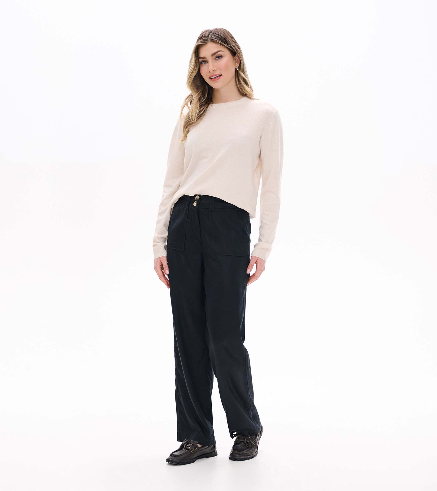 Black wide leg pants on a model from the front, paired with a light sweater and loafers