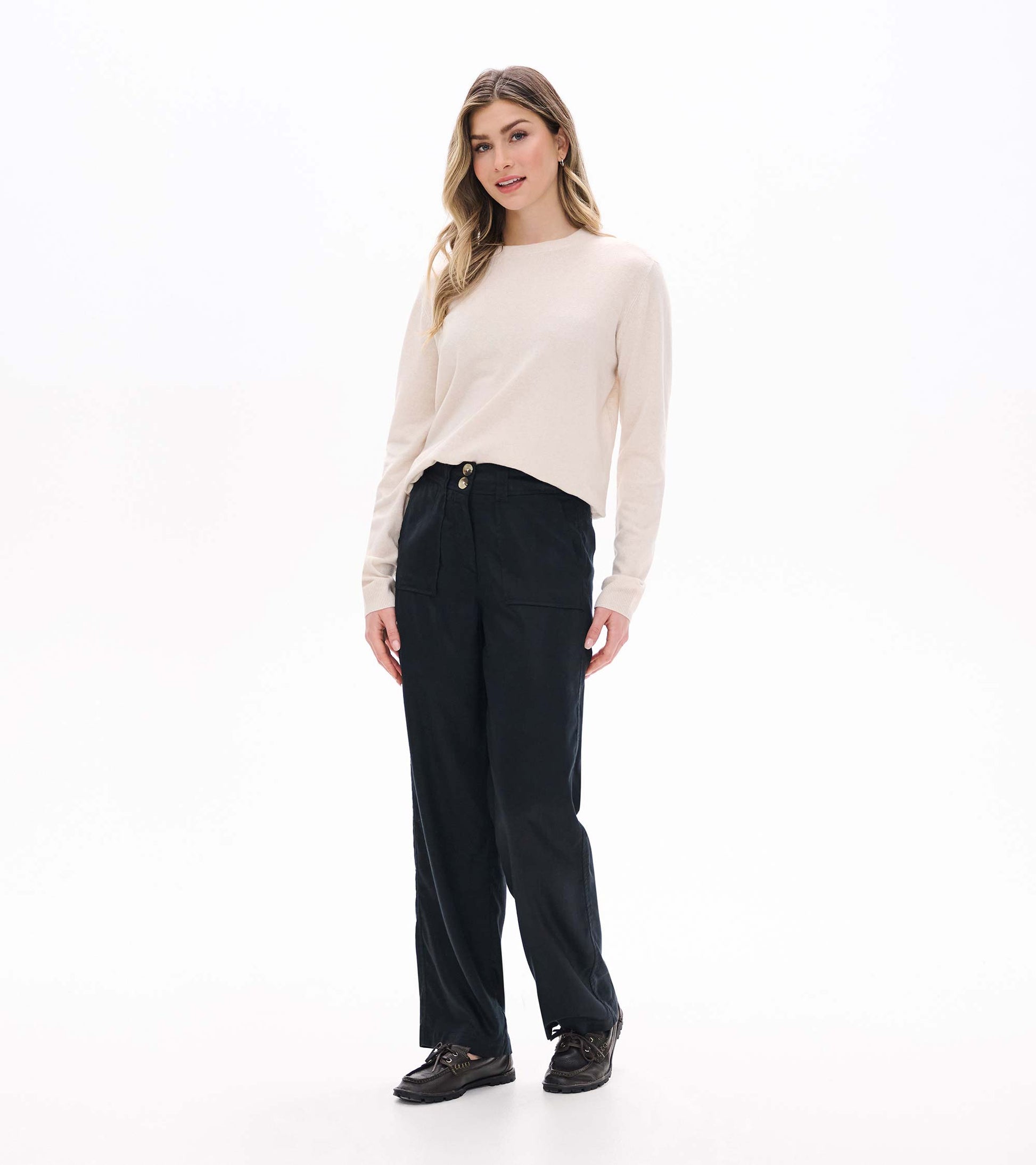 Black wide leg pants on a model from the front, paired with a light sweater and loafers