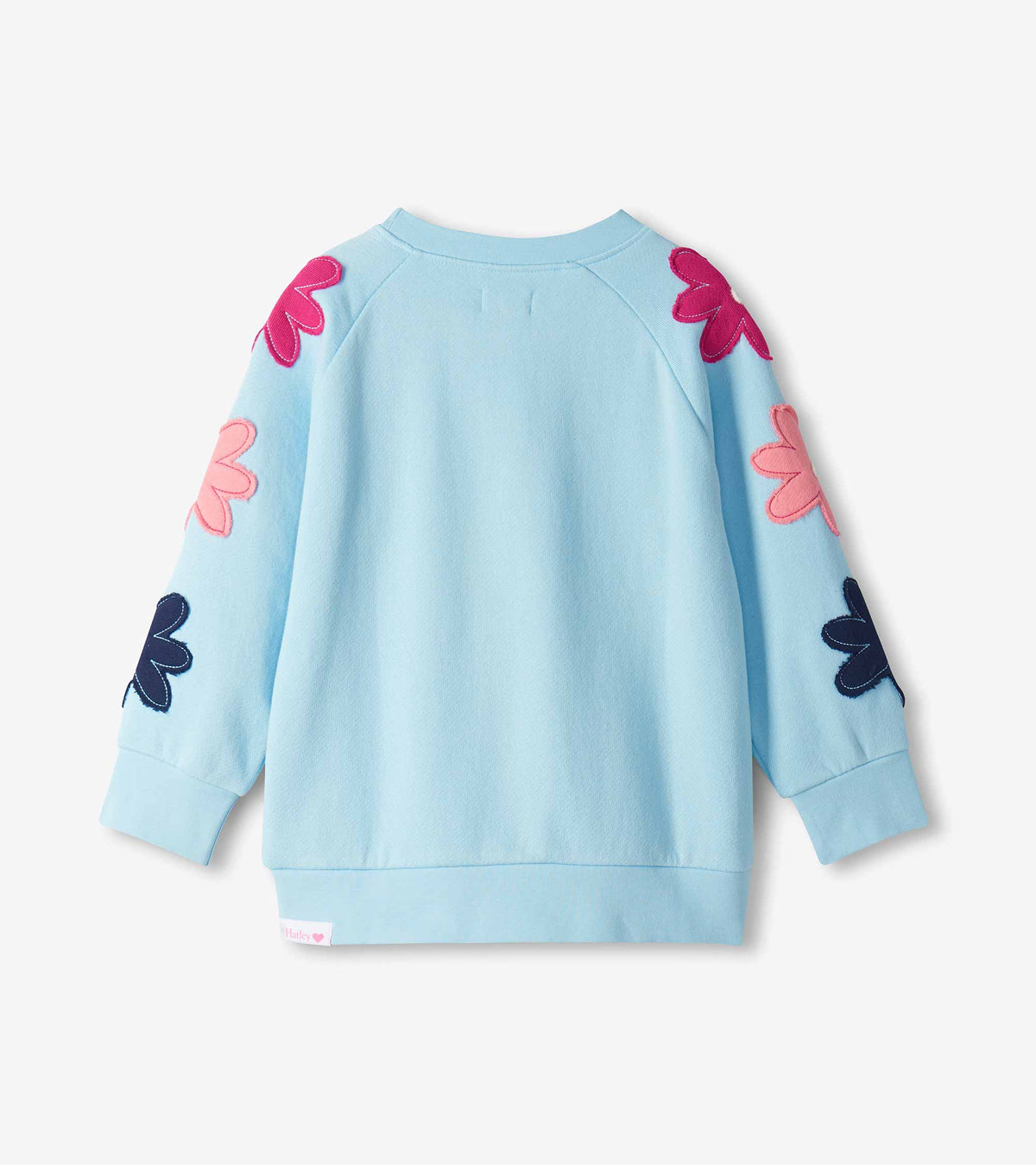 Back view of cool blue pullover with pink, fuchsia, and navy flower appliqués on the sleeves