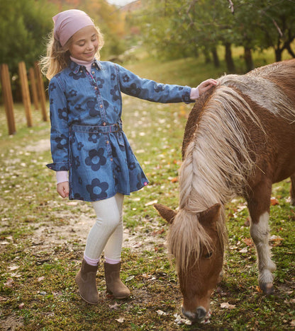 Girl wearing blue flower print shirt dress with belt, shown outdoors beside a pony