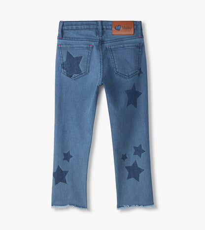 Back view of blue slouchy jeans with dark star print, back pockets, logo patch, and frayed hems