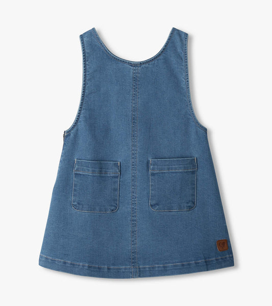 Front view of blue pinafore dress with scoop neckline, center seam, two front patch pockets and small logo patch