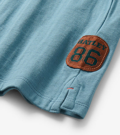 Close-up of side slit hem on blue T-shirt with brown Hatley 86 badge