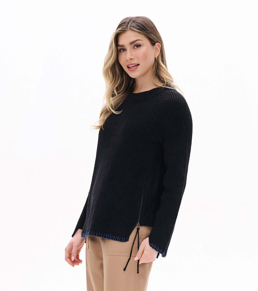 Black raglan sweater with side zip detail, blue stitched hem and cuffs, shown on model at front angle