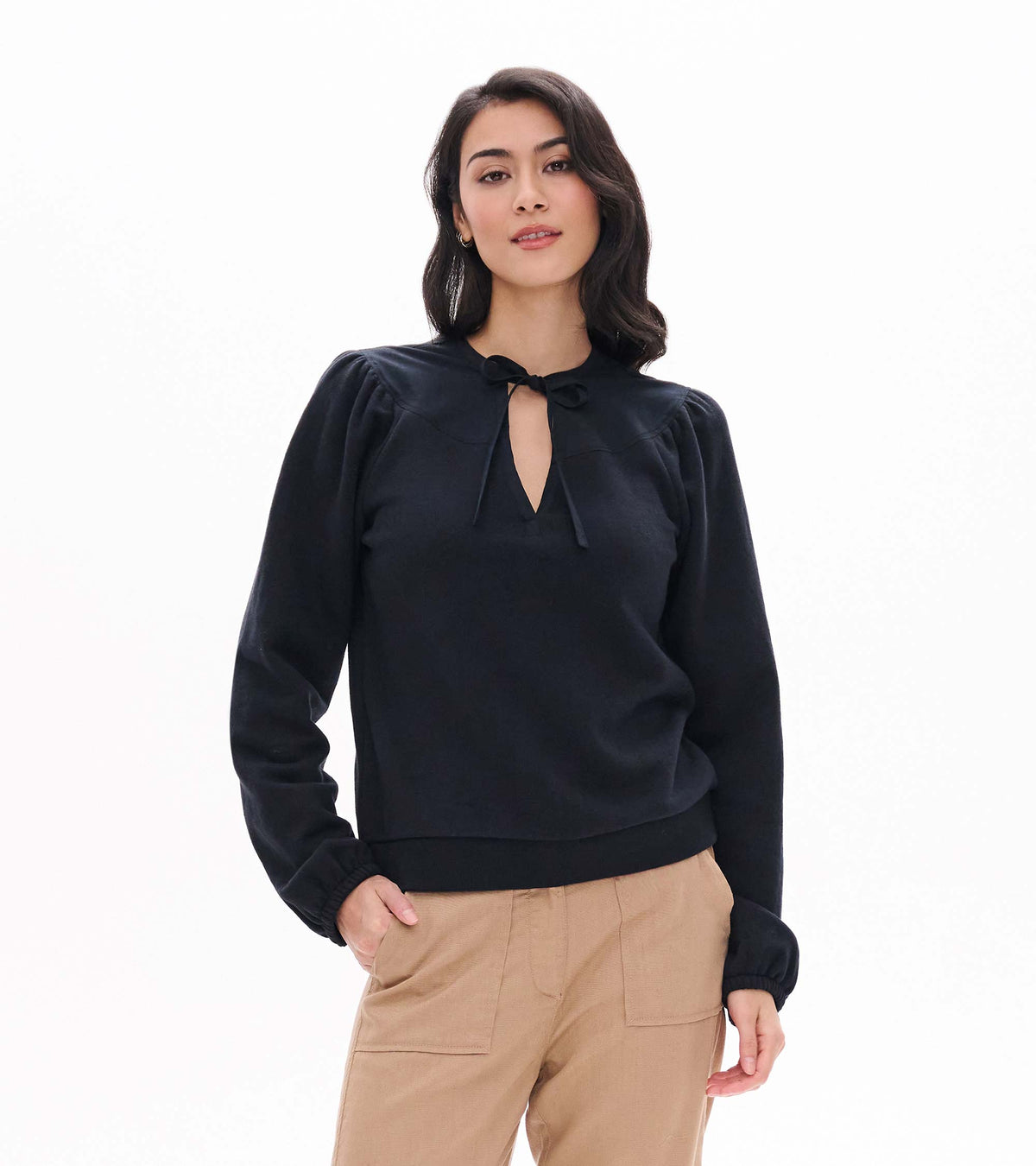 Black top with tie neckline, gathered shoulders, long sleeves and banded hem, shown from the front