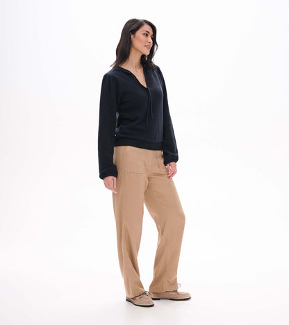 Black long sleeve top shown in side view with tie neckline, gathered shoulders and banded hem