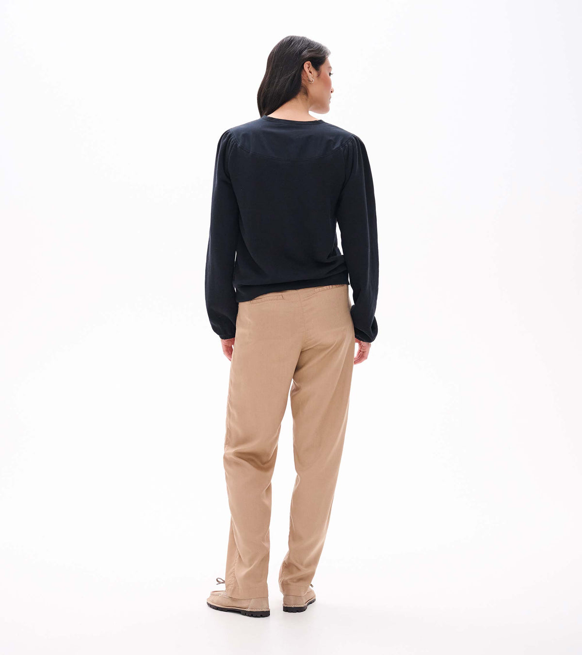 Back view of black long sleeve top with gathered shoulder seams and banded hem