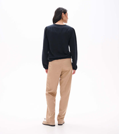 Back view of black long sleeve top with gathered shoulder seams and banded hem
