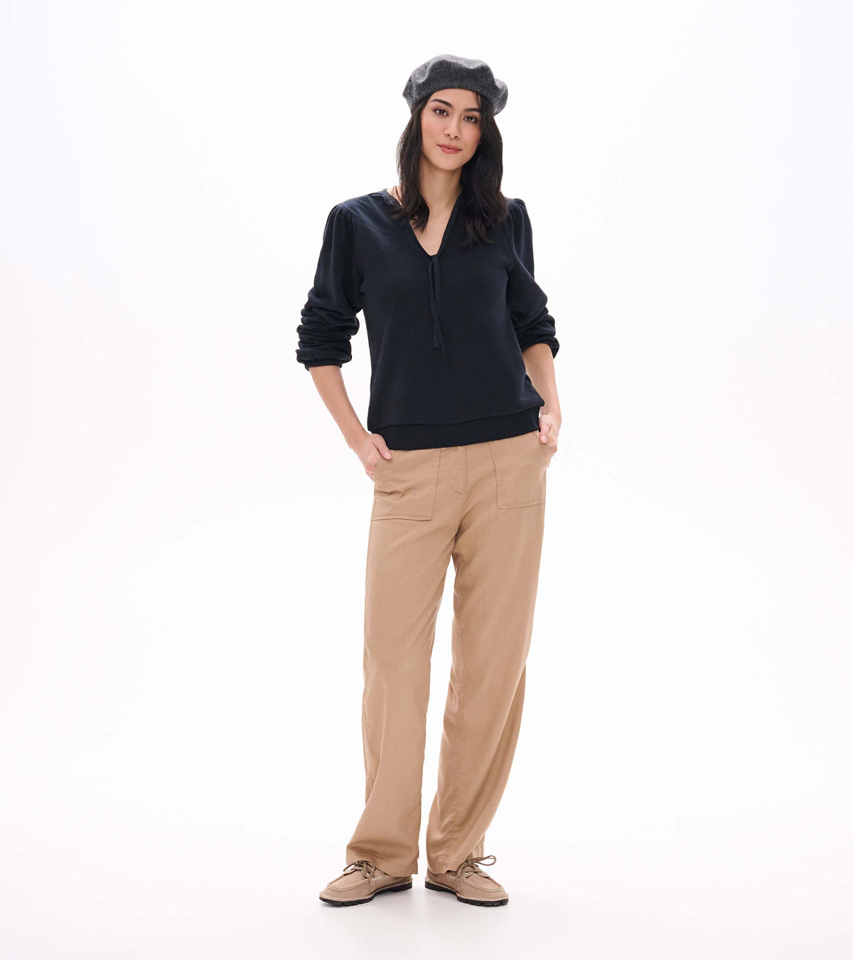 Black long sleeve top with tie neckline and banded hem, shown from the front with sleeves pushed up