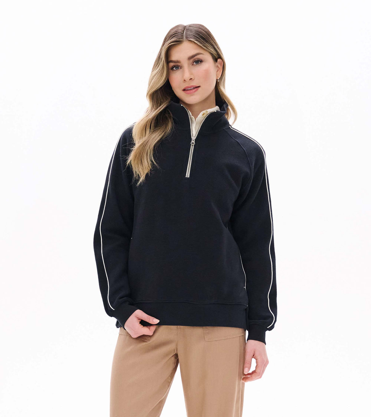 Front view of black 1/4 zip knit top with stand collar and white piping along the sleeves