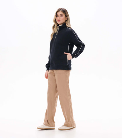 Side view of black 1/4 zip knit top with stand collar, white piping, and side pockets