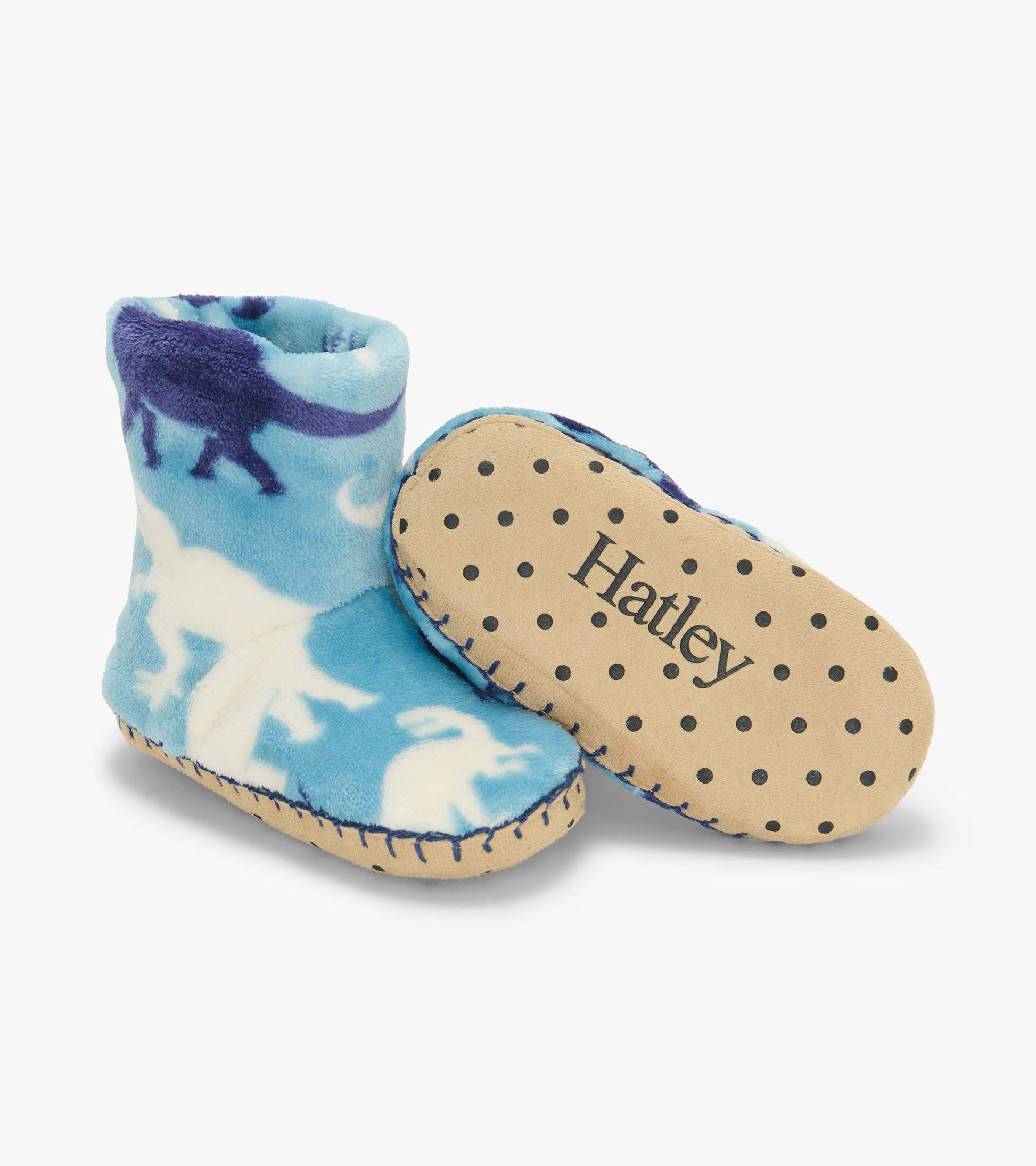 Blue dinosaur print fleece slippers with one sole showing black dots and Hatley logo