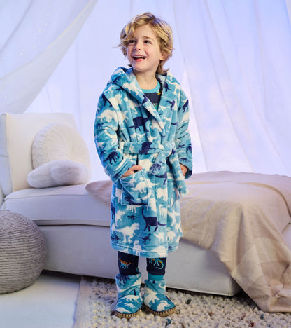 Child wearing a bright blue hooded robe with white and navy dinosaur silhouettes, tie belt, and front pockets