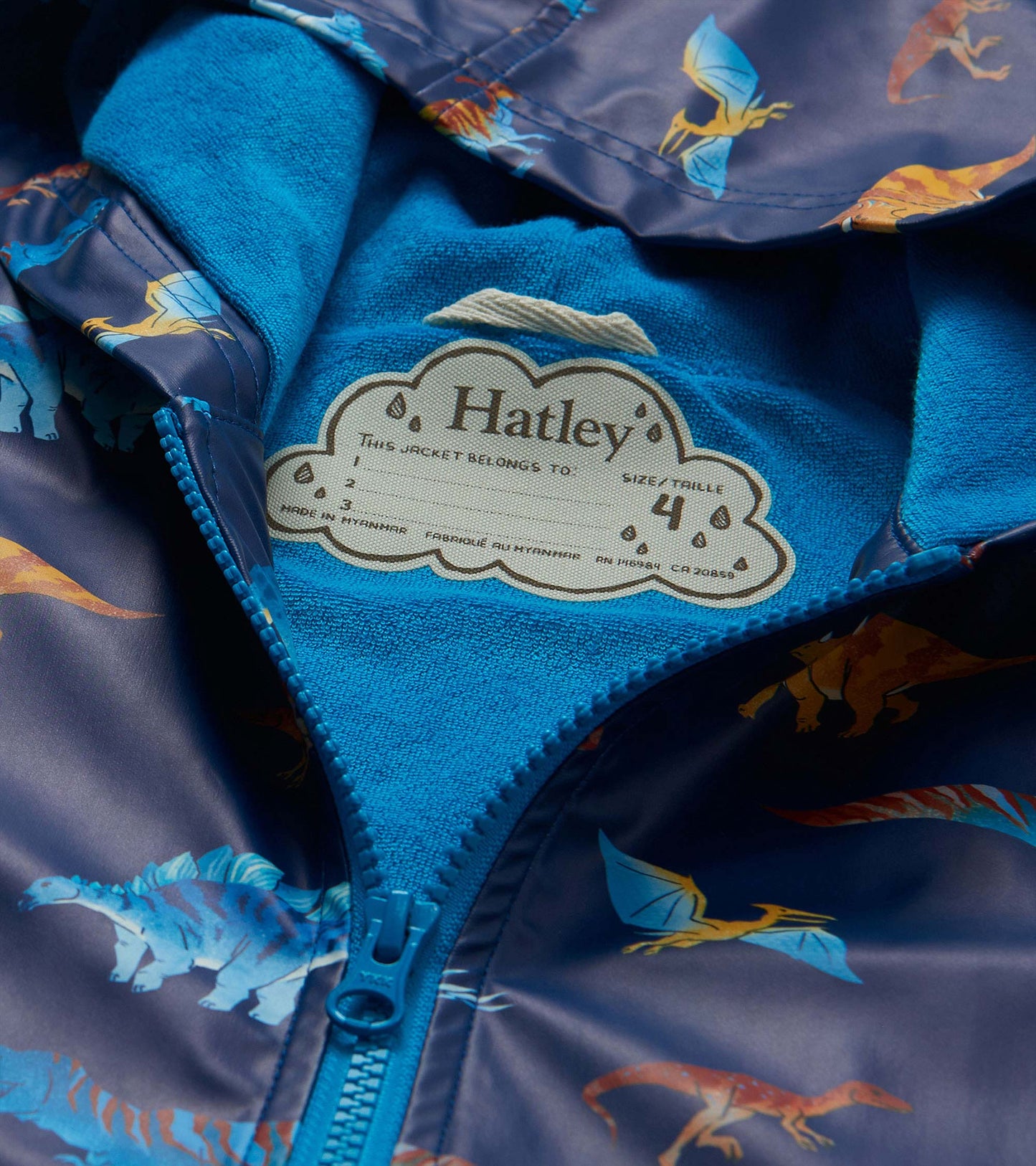 Close-up of bright blue lining, zipper and Hatley name tag inside dinosaur print rain coat