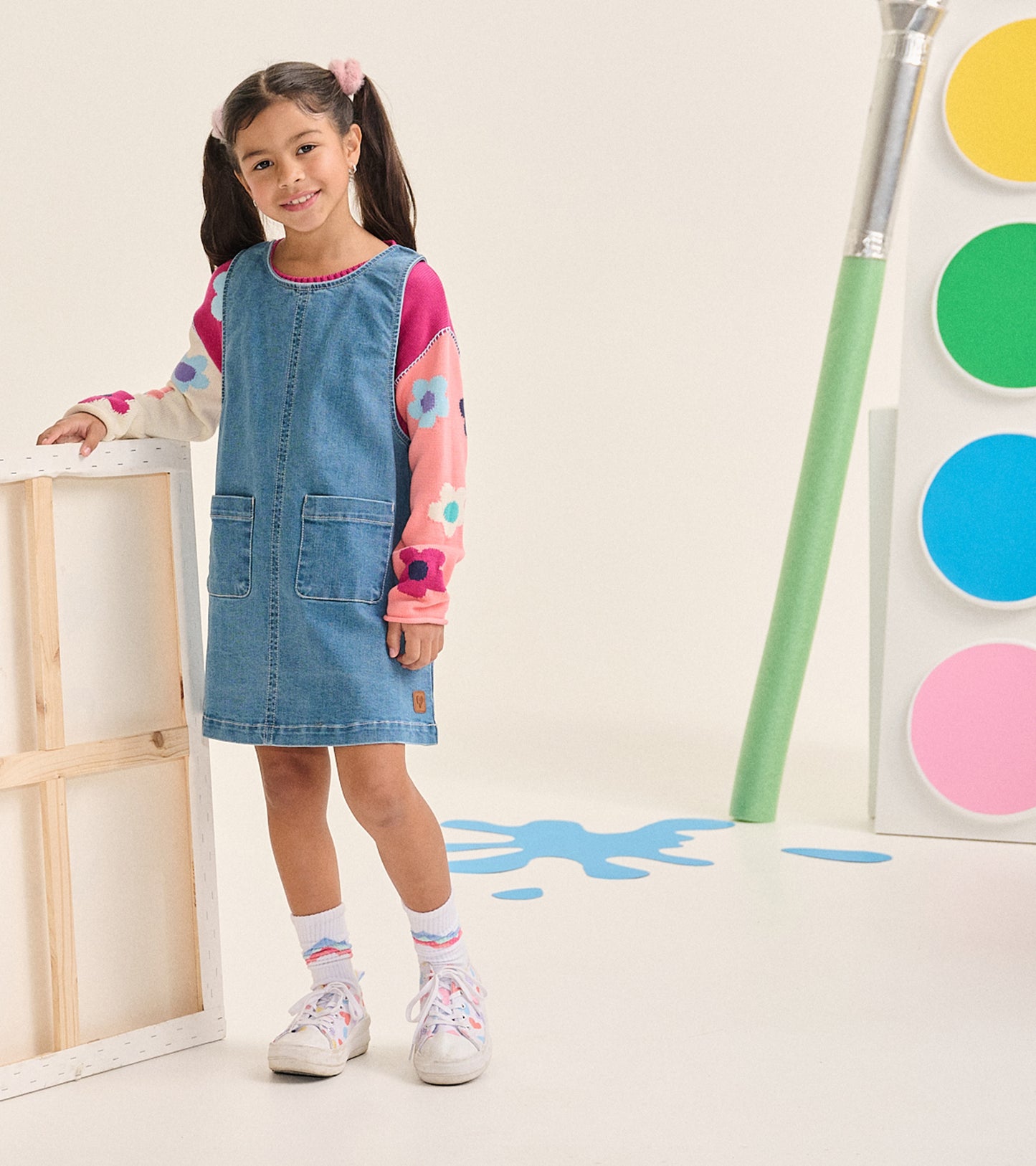 Girl wearing the floral slouchy sweater under a blue denim pinafore dress