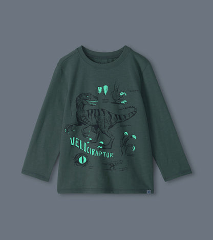 Green boys long-sleeve T-shirt with glow-in-the-dark velociraptor graphic shown in low light