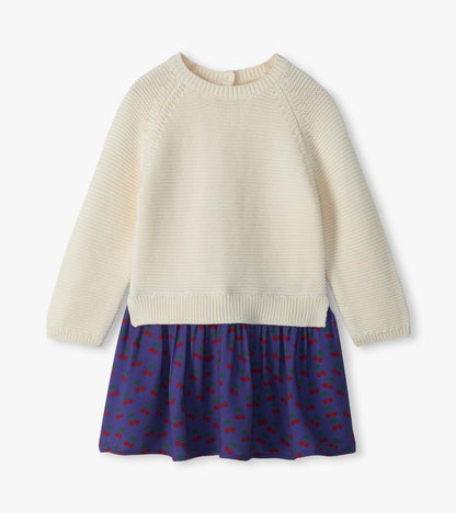 Front view of girls sweater dress with cream knit top and purple skirt with red cherry print