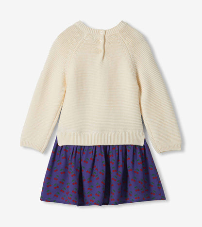 Back view of girls sweater dress with cream knit top, back buttons, and purple cherry-print skirt