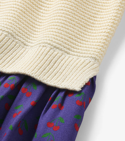 Close-up of the cream knit hem and purple skirt with red cherry print