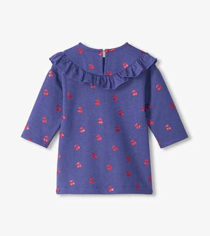 Back view of purple long sleeve dress with red cherry print, ruffle yoke, and button closure