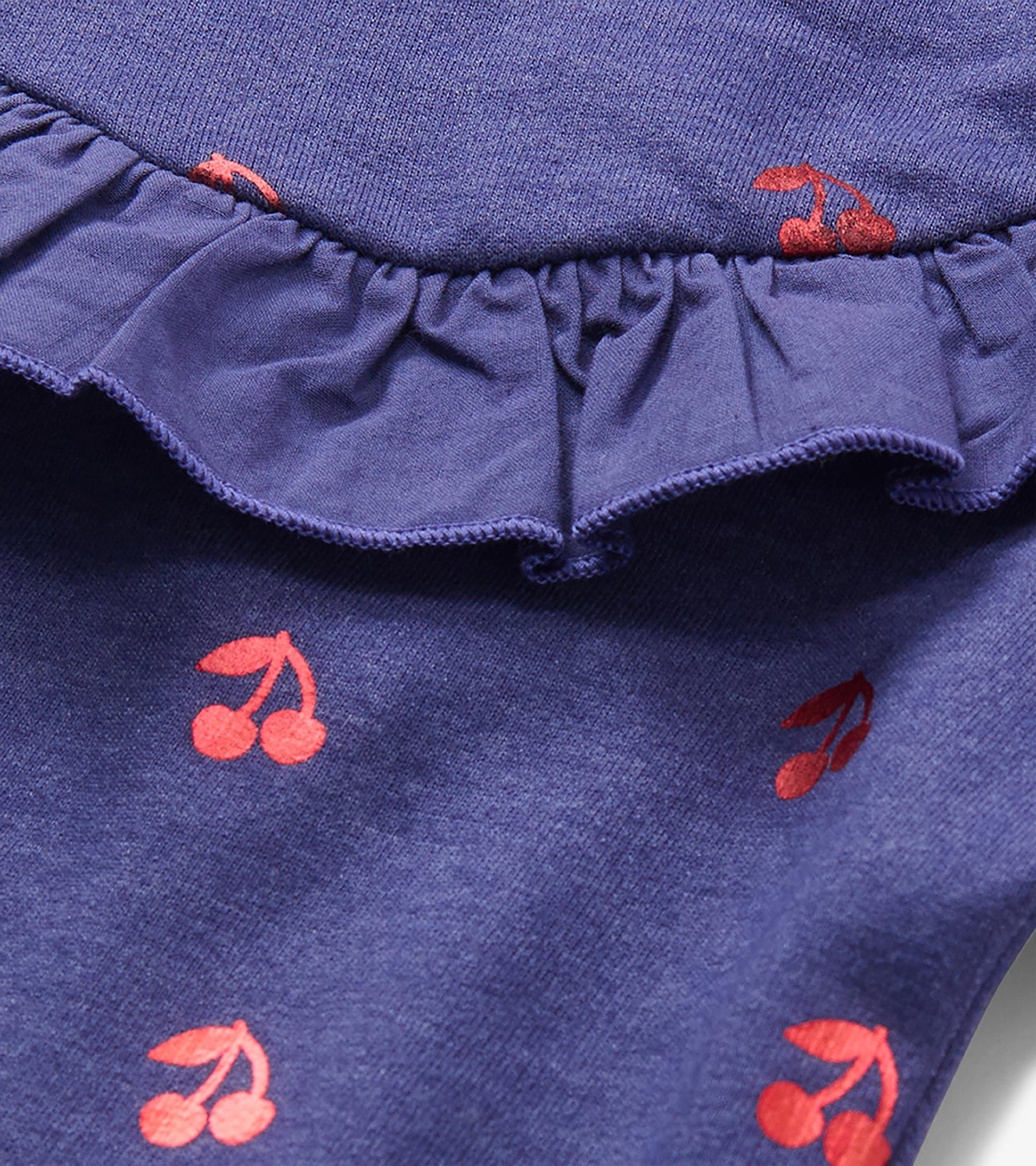 Close-up of blue dress ruffle detail with red cherry print