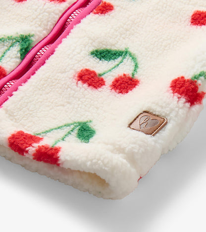 Close-up of cream sherpa jacket with cherry print, pink zipper trim and small logo patch