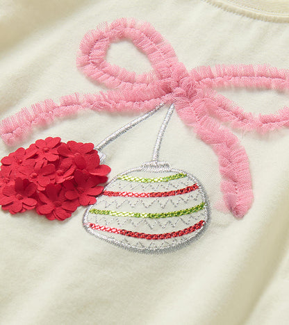 Close-up of pink bow and ornament appliqué with red floral detail on ivory T-shirt