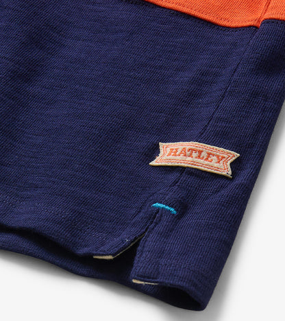 Close-up of navy hem with side slit and Hatley logo tag on boys colourblock polo shirt