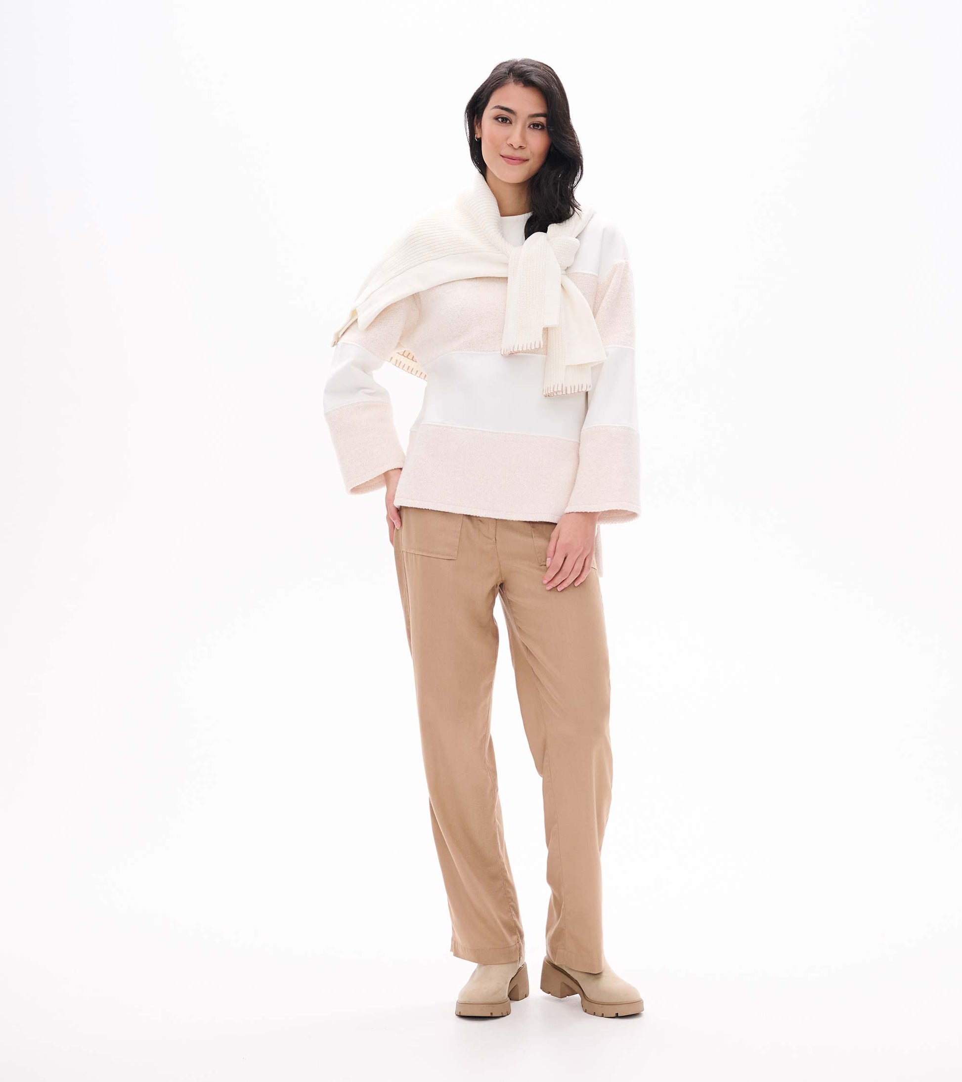 Woman wearing an oatmeal long sleeve top with wide horizontal panels and relaxed sleeves