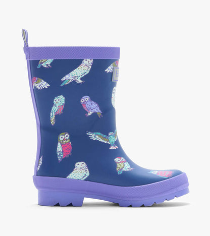 Side view of a navy kids rain boot with colorful owl print, lavender trim, and treaded sole