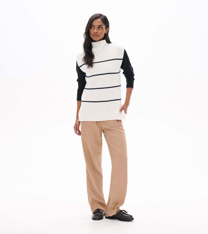 Front view of cream sleeveless striped sweater tunic layered over a black long sleeve top
