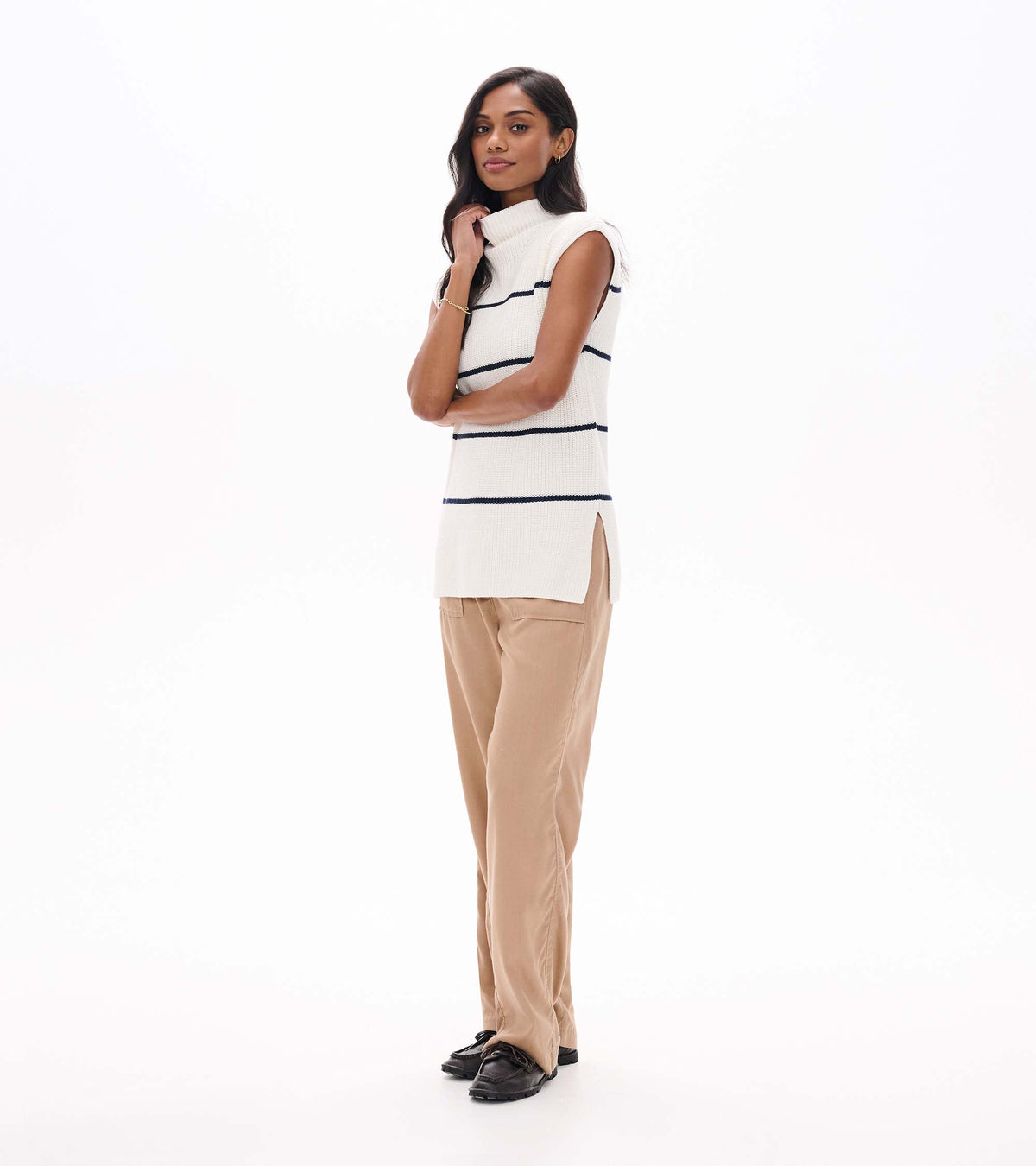 Side view of cream sleeveless sweater tunic with navy stripes and side slit on model