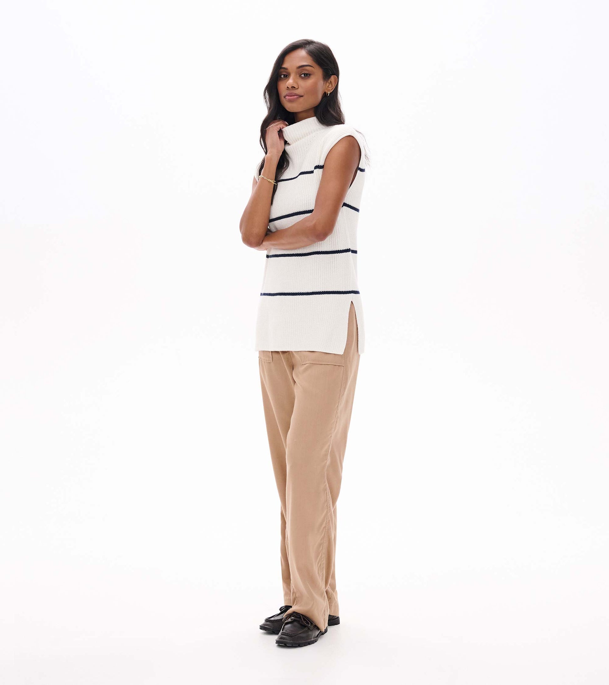 Side view of cream sleeveless sweater tunic with navy stripes and side slit on model