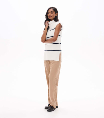 Side view of cream sleeveless sweater tunic with navy stripes and side slit on model