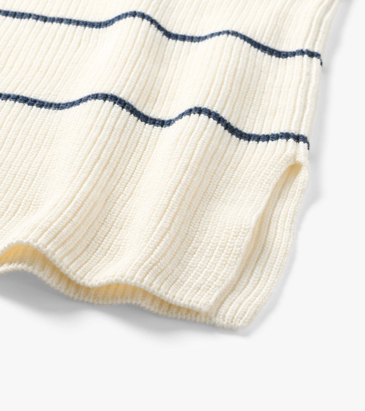 Close-up of cream ribbed sweater tunic hem with thin navy horizontal stripes