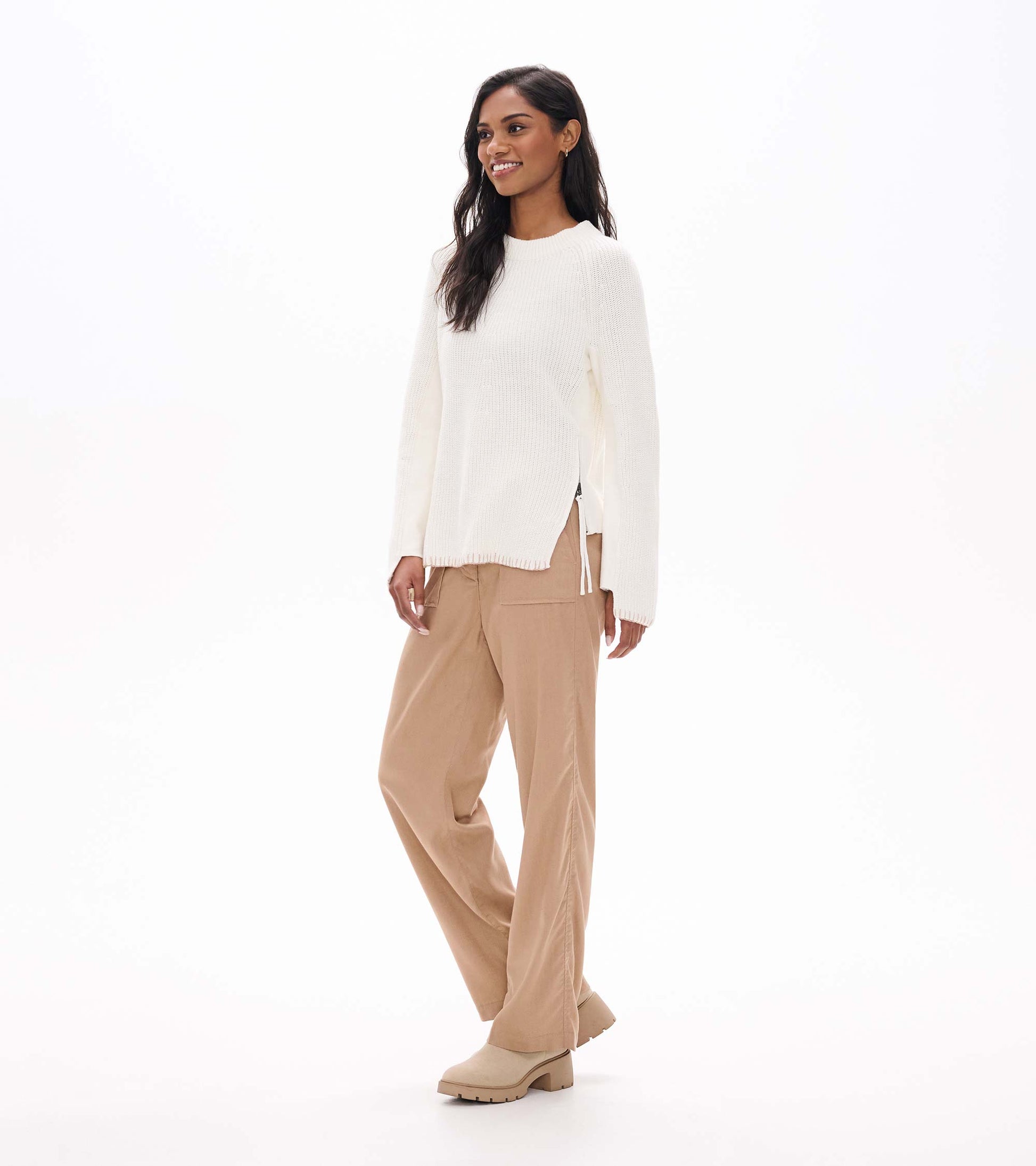 Three-quarter front view of cream raglan sweater with side zip opening at the hem