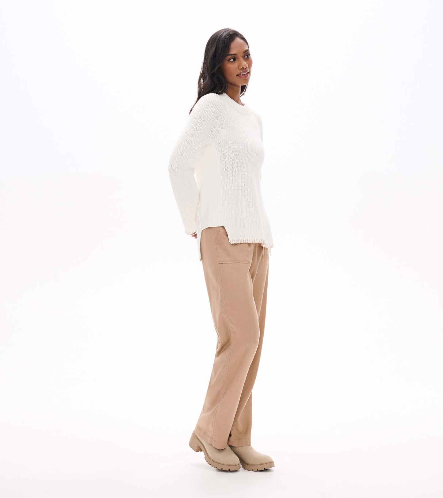 Side view of cream raglan sweater showing the side zip opening and split hem