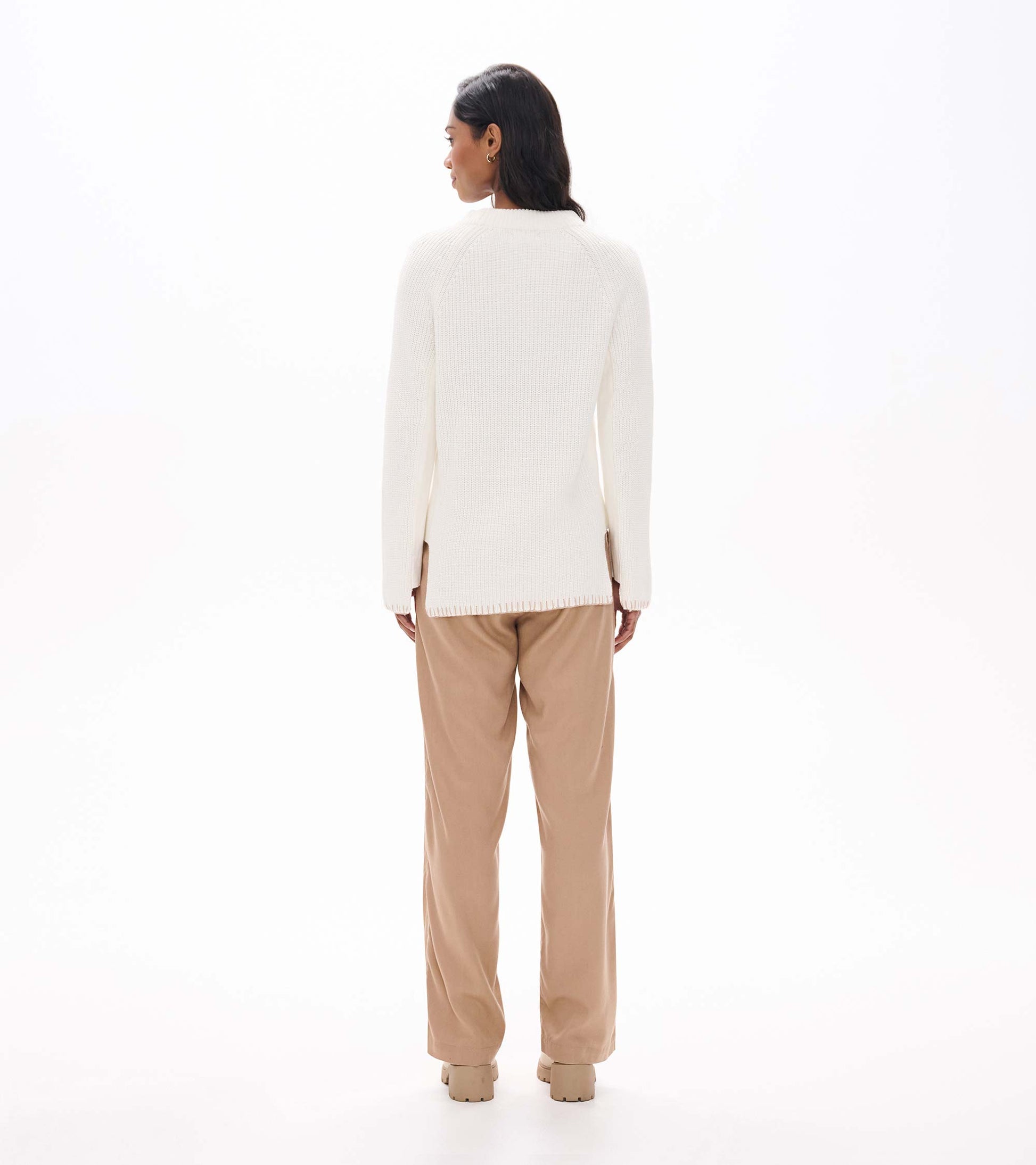 Back view of cream raglan sweater with side hem zips, worn with tan pants