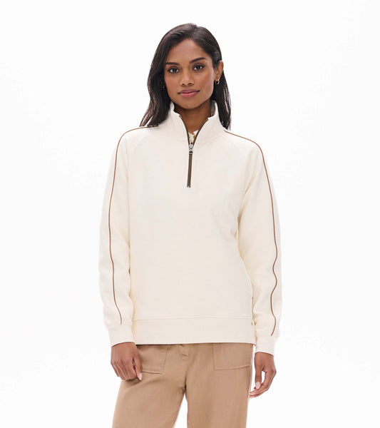 Front view of cream 1/4 zip top with stand collar and brown piping along the sleeves