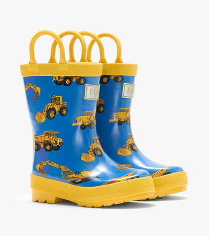 Pair of blue kids rain boots with yellow handles and trim, printed with construction trucks