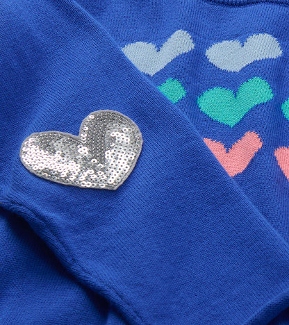 Close-up of silver heart elbow patch and knitted heart stripes on blue sweater