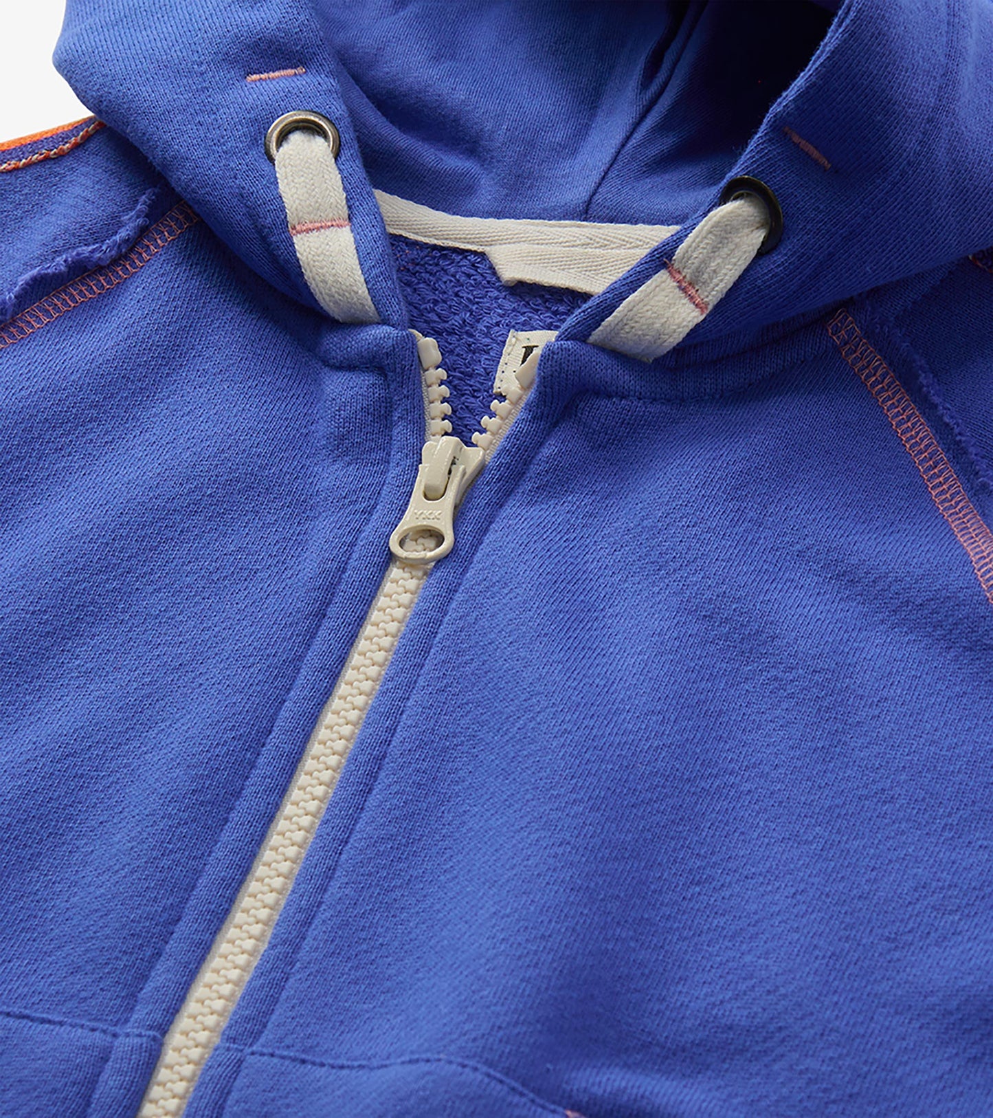 Close-up of blue hoodie neckline with white zipper, hood drawcord, and pink contrast stitching